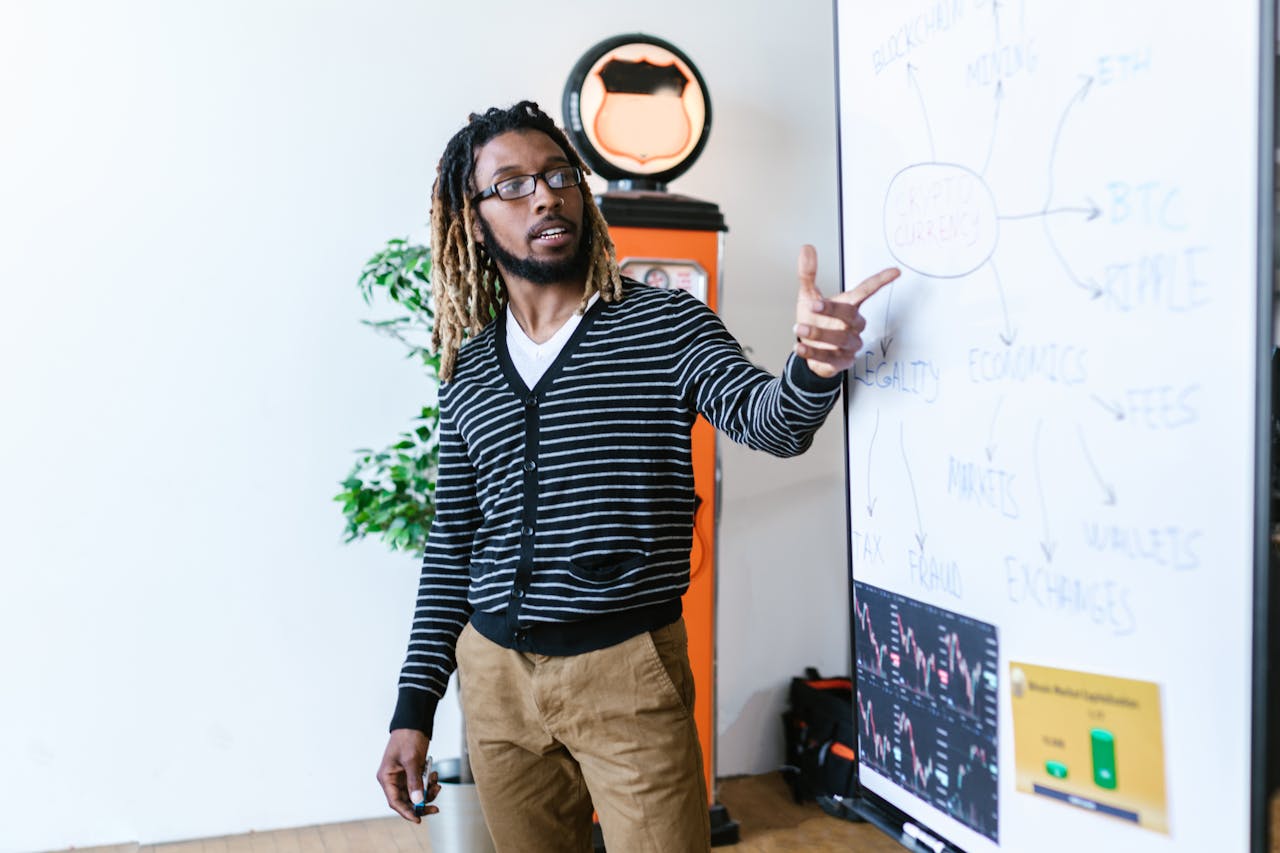 Man explaining cryptocurrency concepts on a whiteboard in a modern office setting.